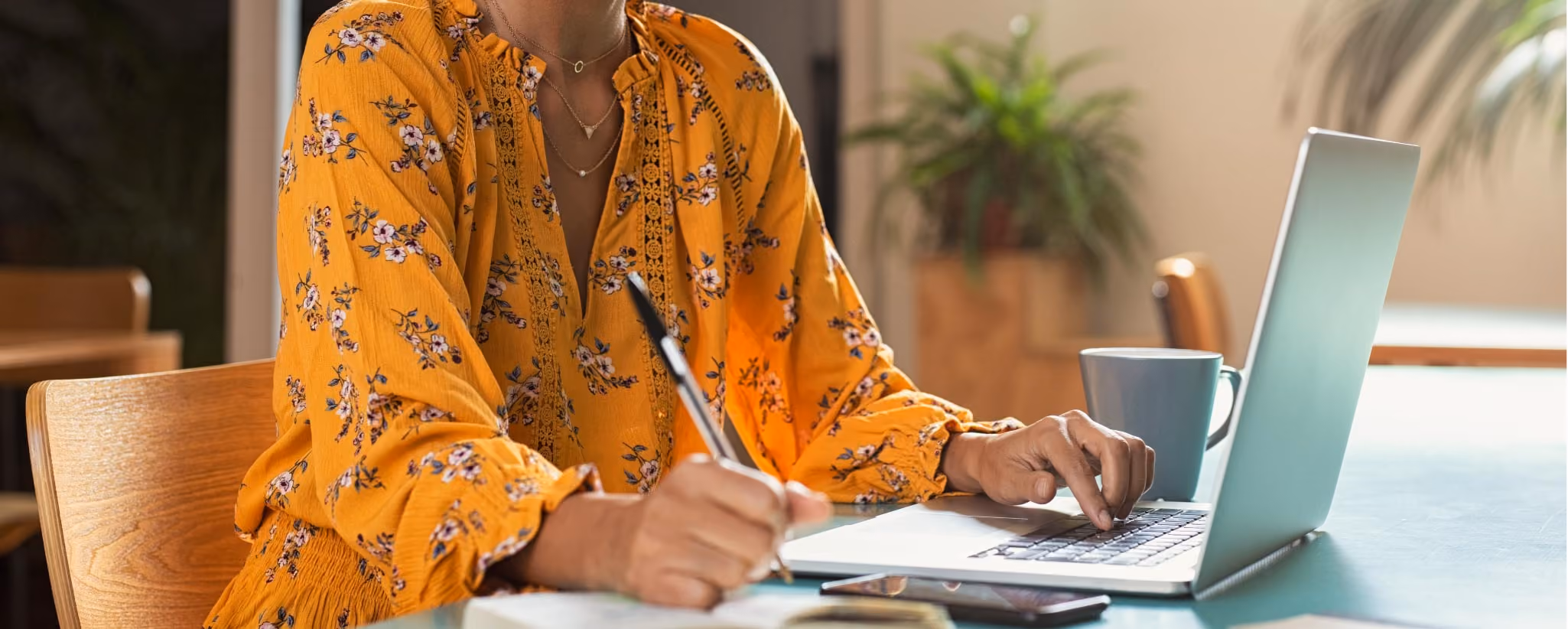 Woman in orange shirt studying at her computer