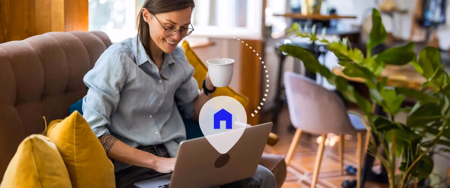Woman wearing glasses smiles as she manages her property remotely via her laptop.
