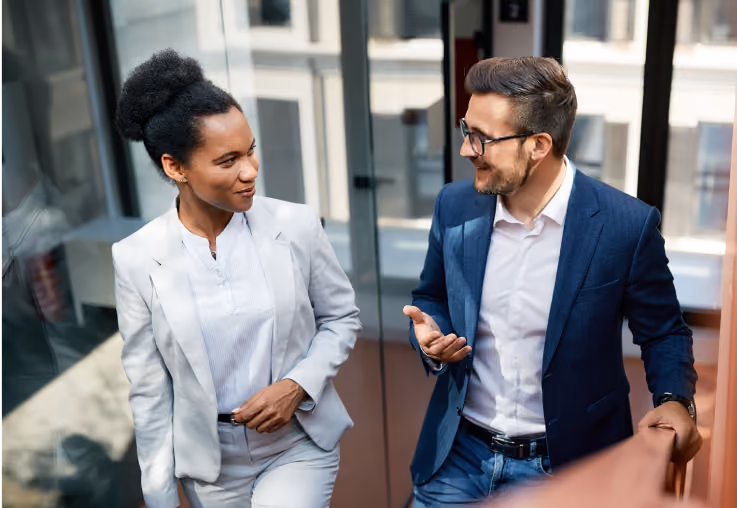Two business professionals talking while walking up a stairwell in an office building.