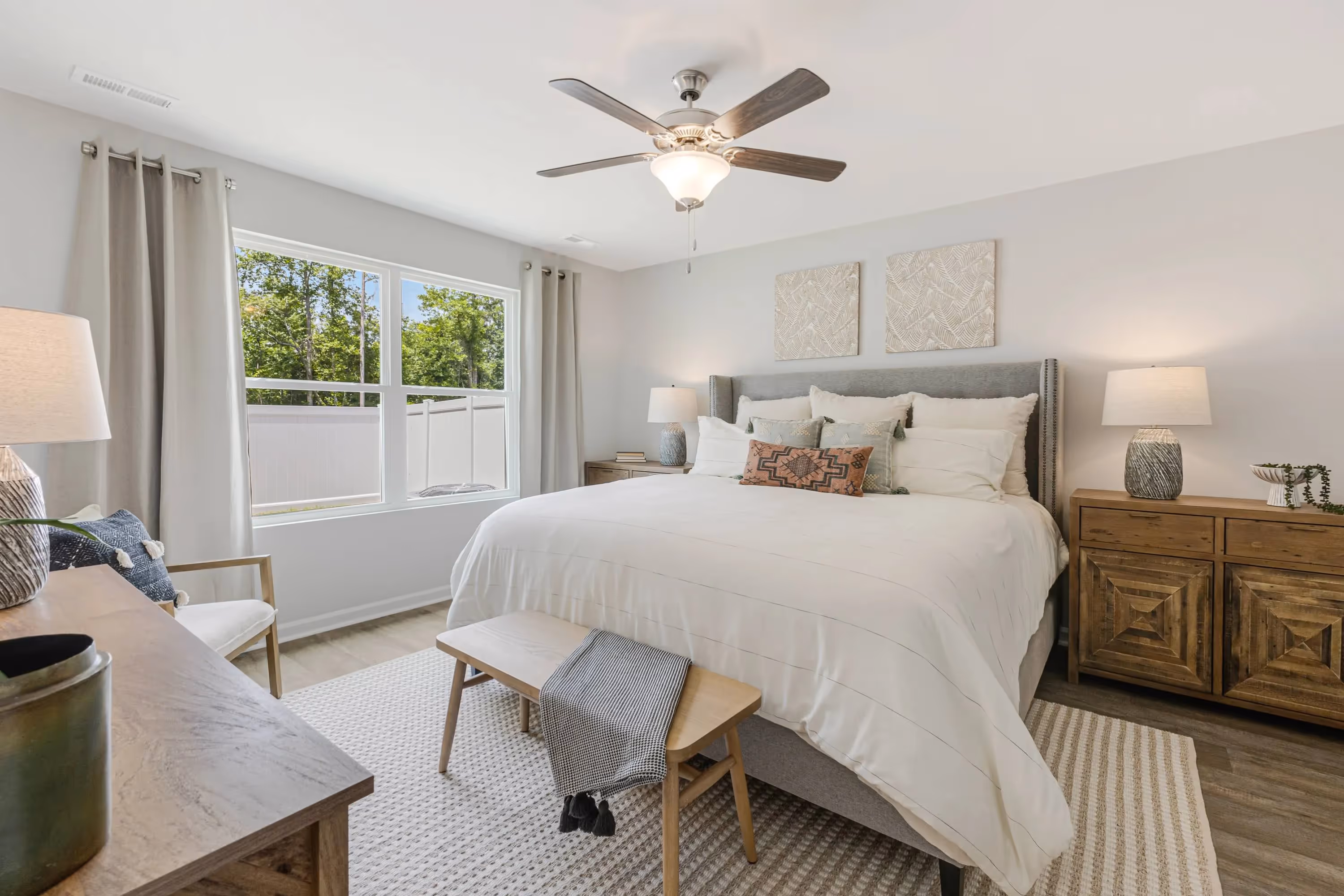 Bright and spacious master bedroom in a home at Landing at Stone Chimney, Supply NC, with a large bed, modern furnishings, and a ceiling fan.