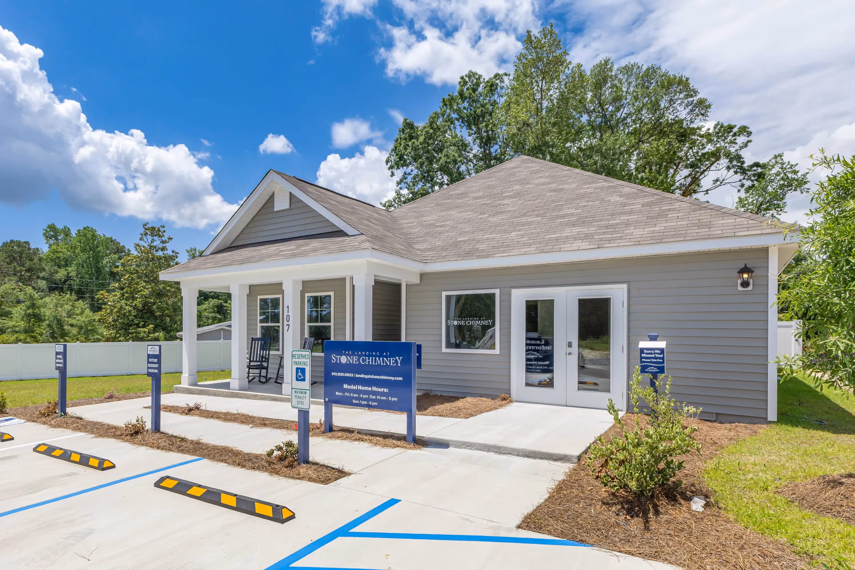 Exterior of the Landing at Stone Chimney community clubhouse or sales office in Supply, NC, with light gray siding, white pillars, and prominent signage