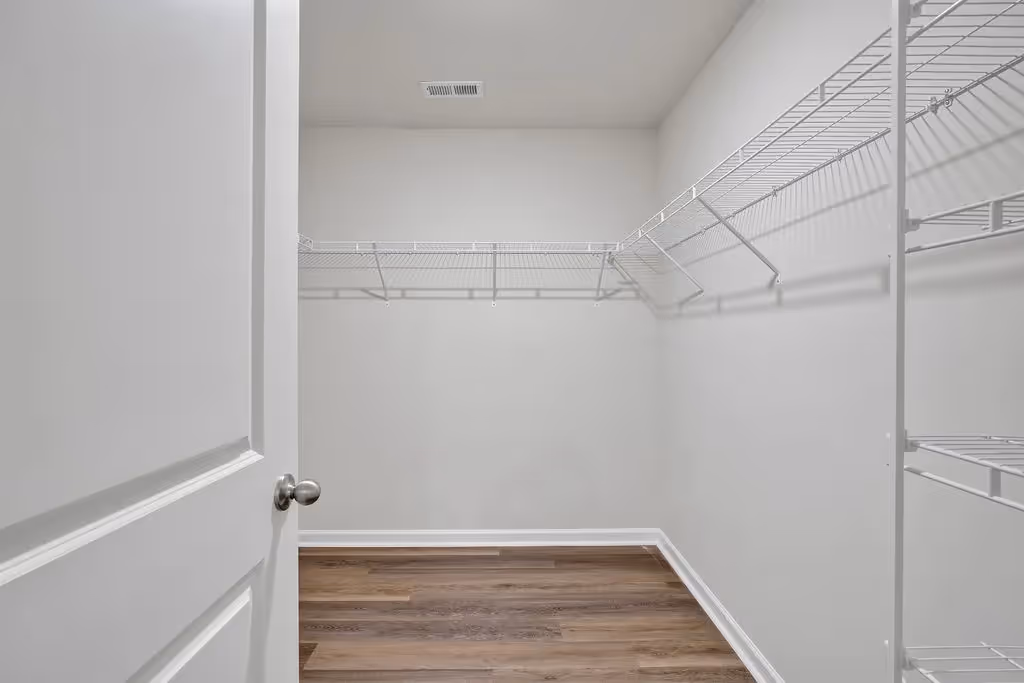 Spacious walk-in closet in a home at Landing at Stone Chimney, Supply NC, featuring white wire shelving and wood-look flooring
