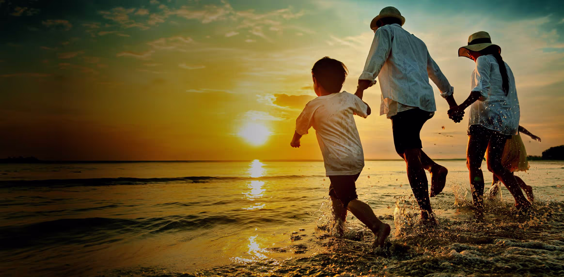 A family of three is walking on the beach.