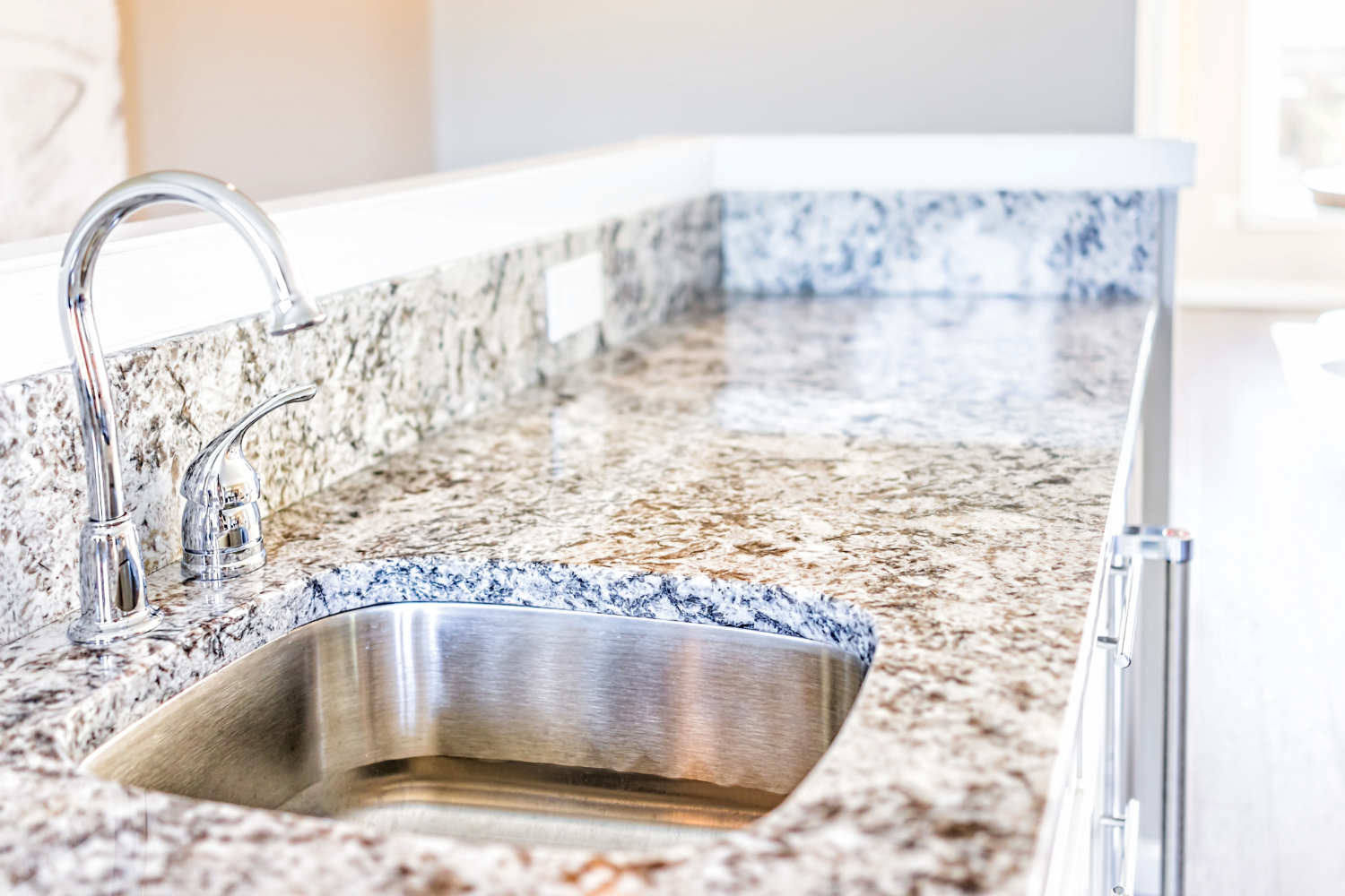 Granite countertop with sink and chrome faucet.