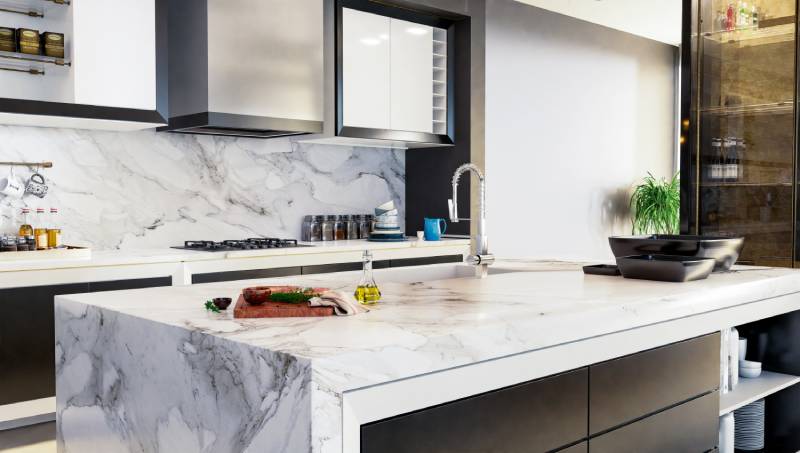 Modern kitchen with white marble island and backsplash.