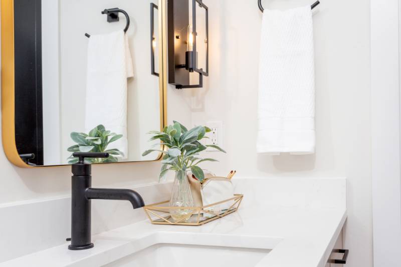 Bathroom vanity with white quartz countertop and black faucet.