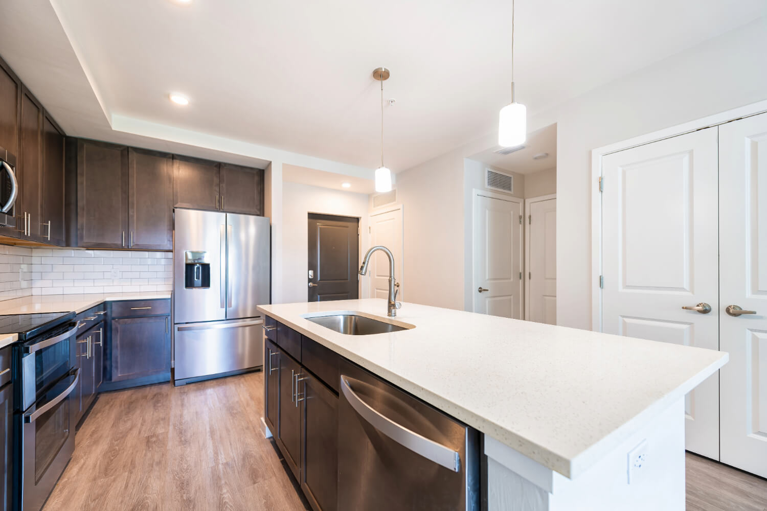 Kitchen with dark cabinets and white quartz island countertop.