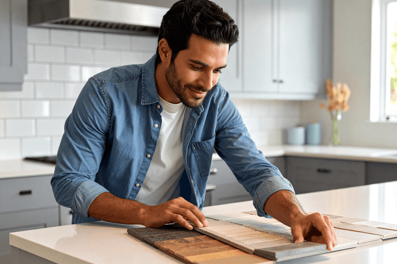 A focused homeowner standing at a kitchen island reviewing countertop material samples