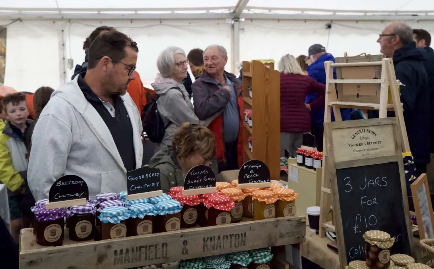 Market stall with jars of chutney labeled beetroot, gooseberry, tomato & sweet pepper, and mango & peach, and a sign advertising 3 jars for £10.