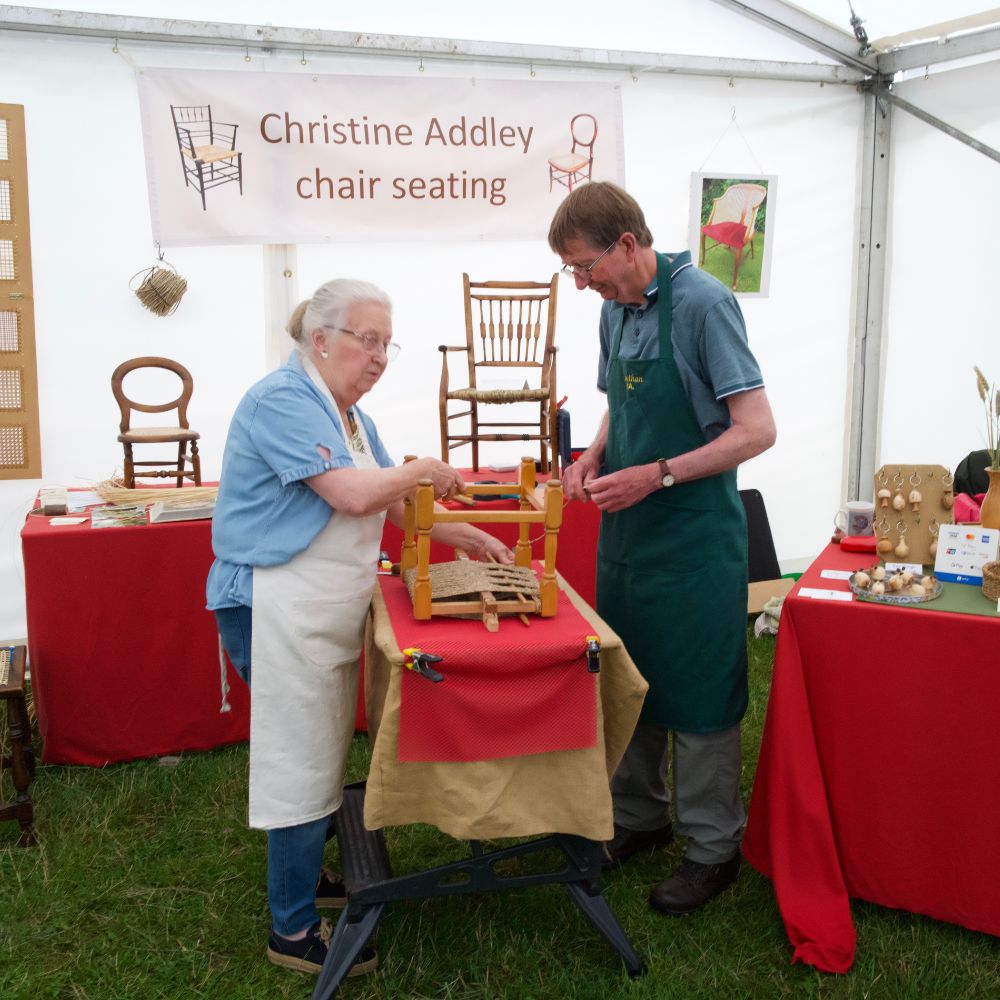 Two trade stand owners stood talking while looking at a chair that they are working on