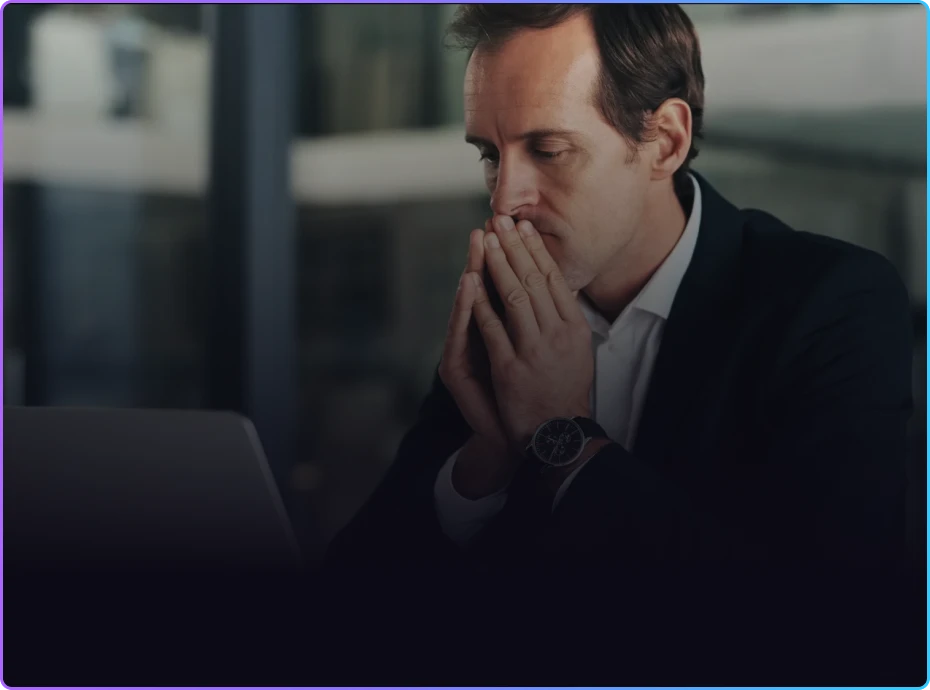 Attorney sitting at a desk with hands pressed to face, appearing stressed while looking at a laptop