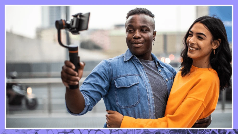 Two content creators filming a vertical video with a smartphone on a stabilizer.
