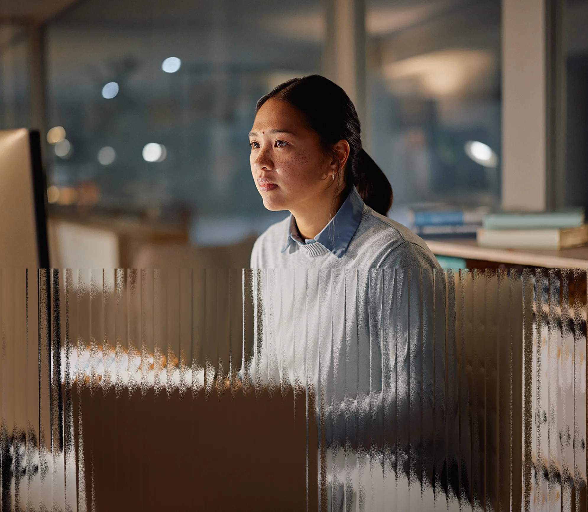 Legal professional reviewing case files on a desktop monitor in an office at night.