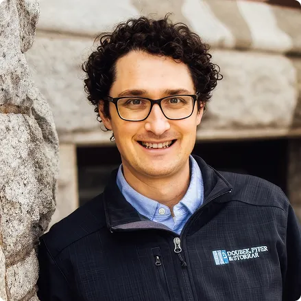 Headshot of an attorney in a Doubek, Pyfer & Storrar jacket standing outside a stone building.