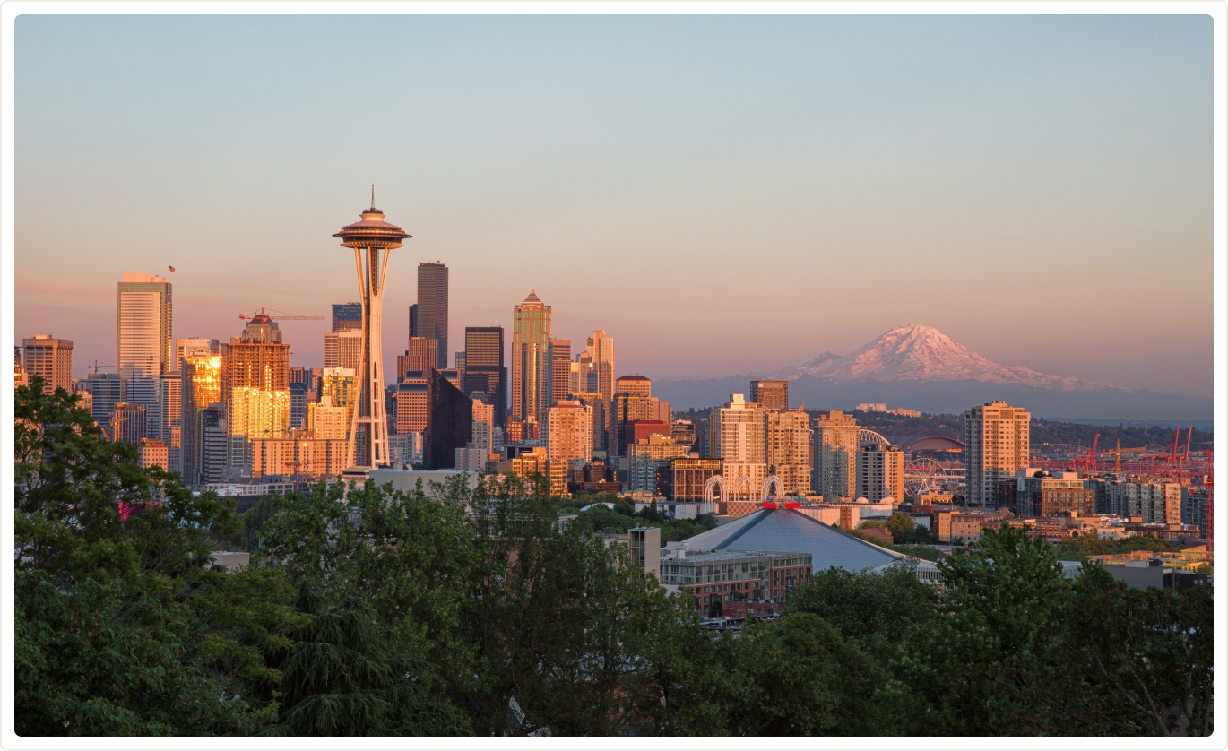 Aerial view of the Seattle skyline at golden hour, overlooking the mountains.