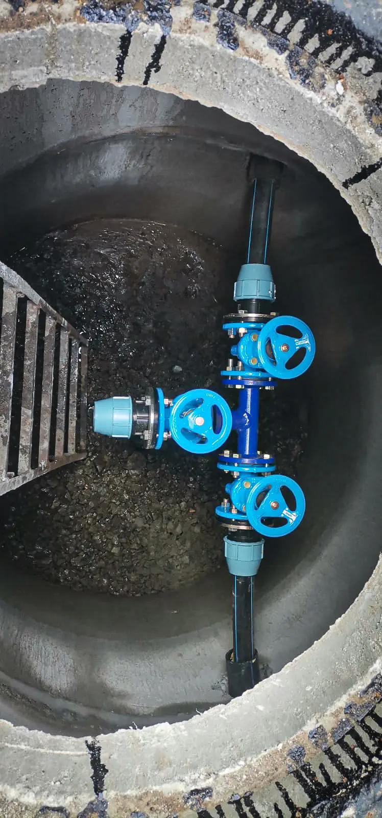 Underground view of new blue gate valve system in concrete water chamber.