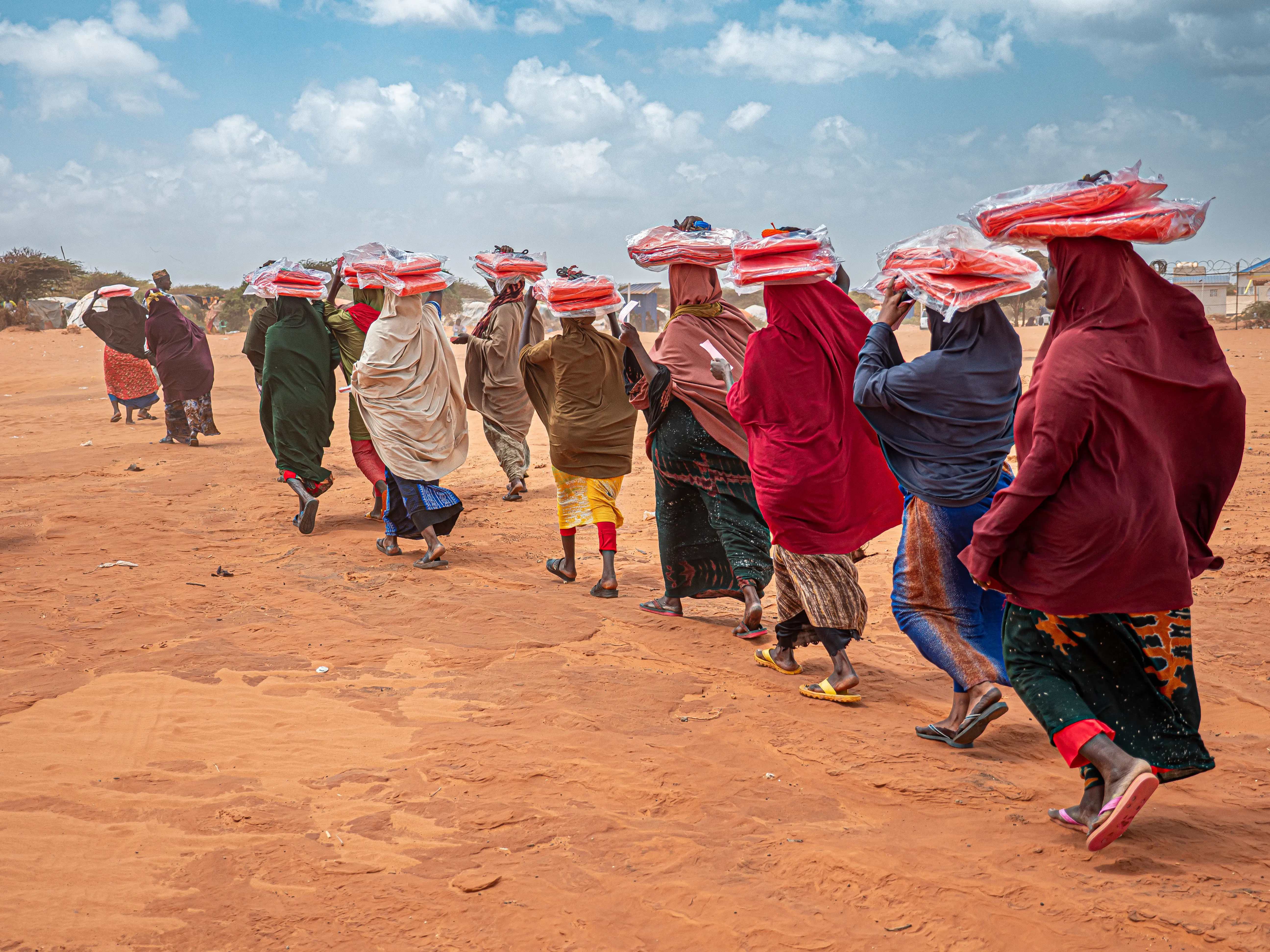 Women carry shelter supplies in flood-affected displacement camp in Somalia