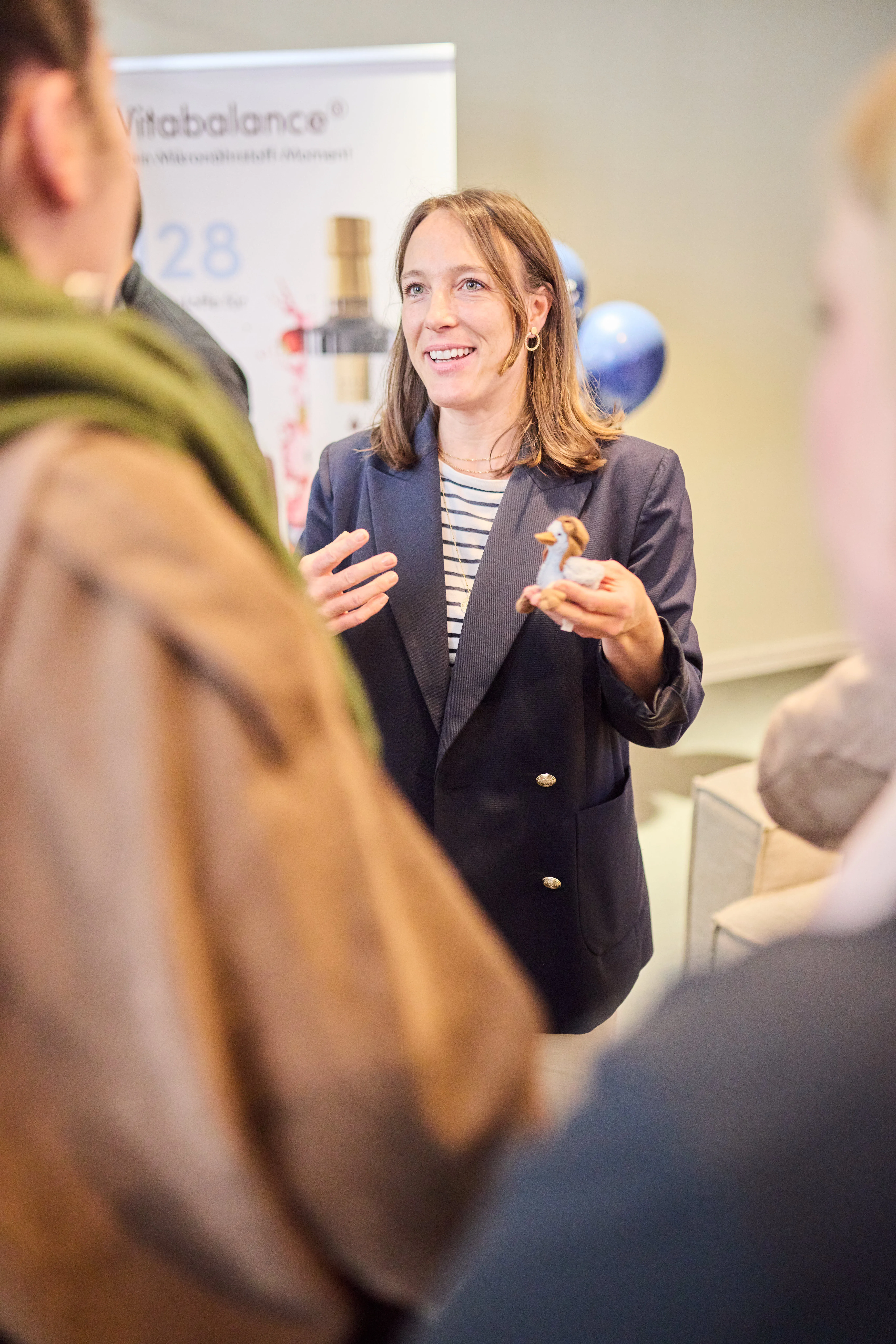 Frau im dunkelblauen Blazer im Gespräch mit Gästen bei einem PR-Event