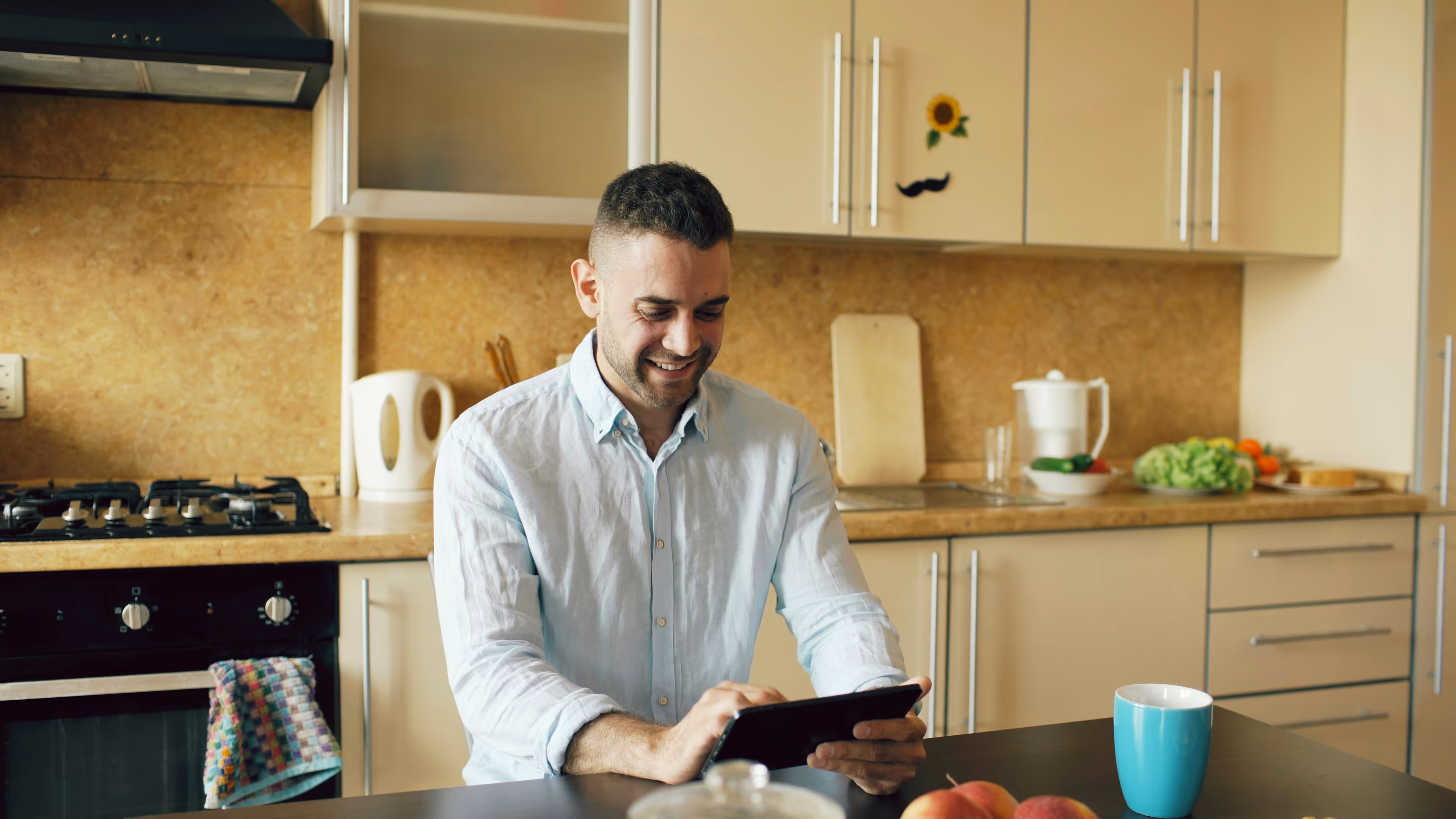 Person sitting behind a kitchen table working with a tablet