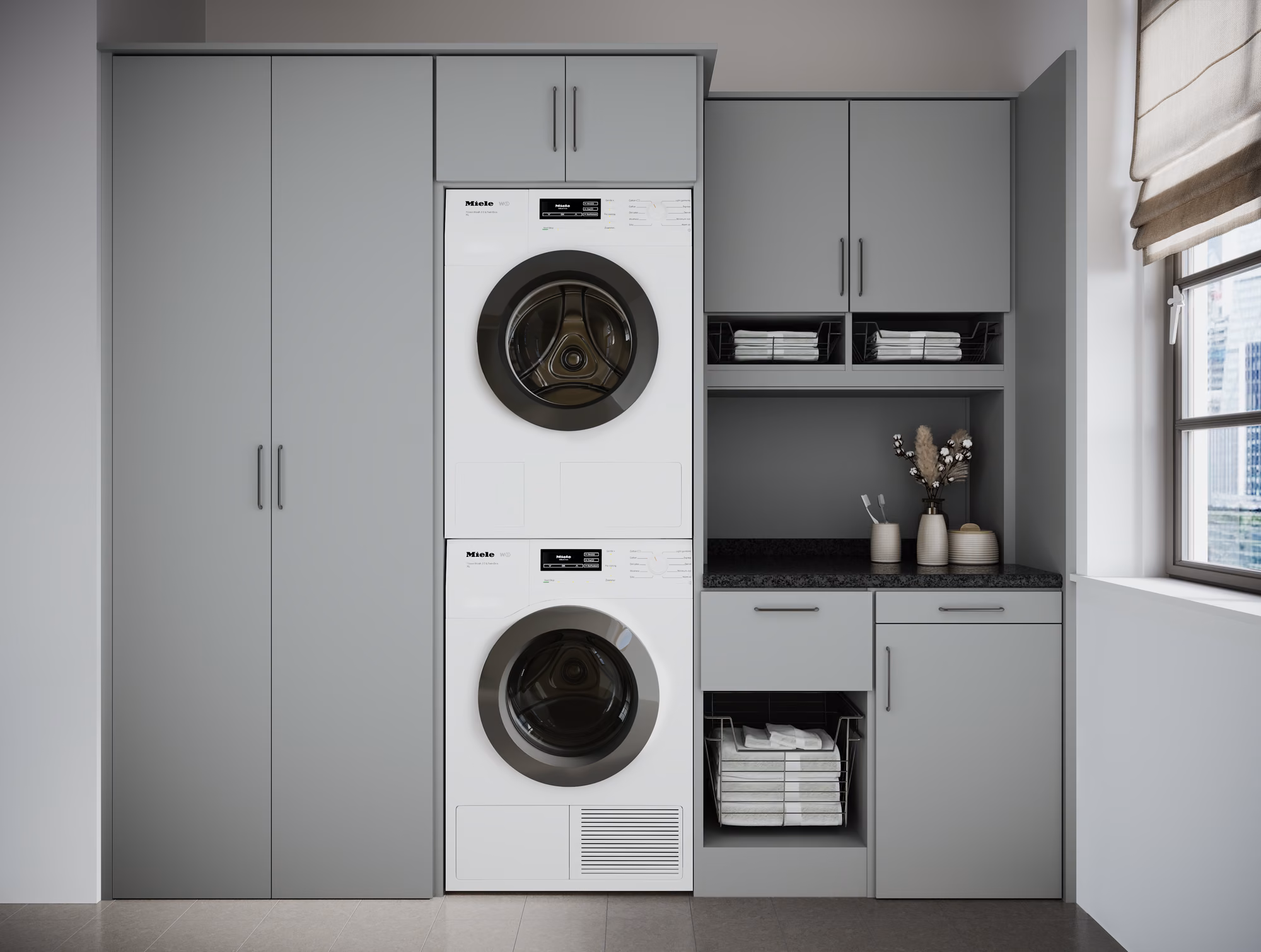Gray cabinet laundry room with a stacked front-load washer and dryer flanked by a full-height storage tower, pull-out wire baskets, and a dark stone countertop.