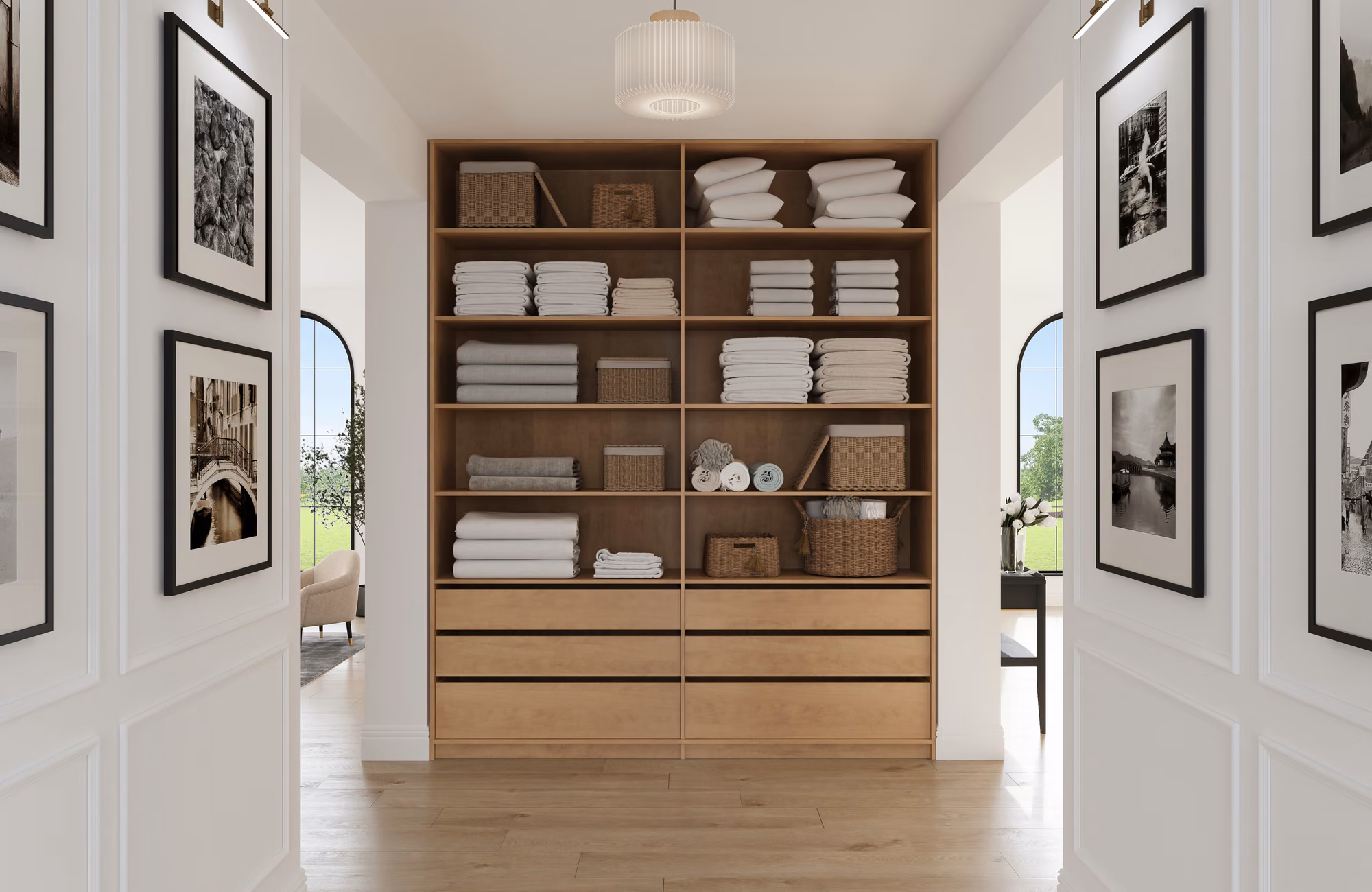 Oak linen closet with open shelves of neatly stacked white towels and sheets, woven baskets, and three deep drawers below, in a bright hallway.