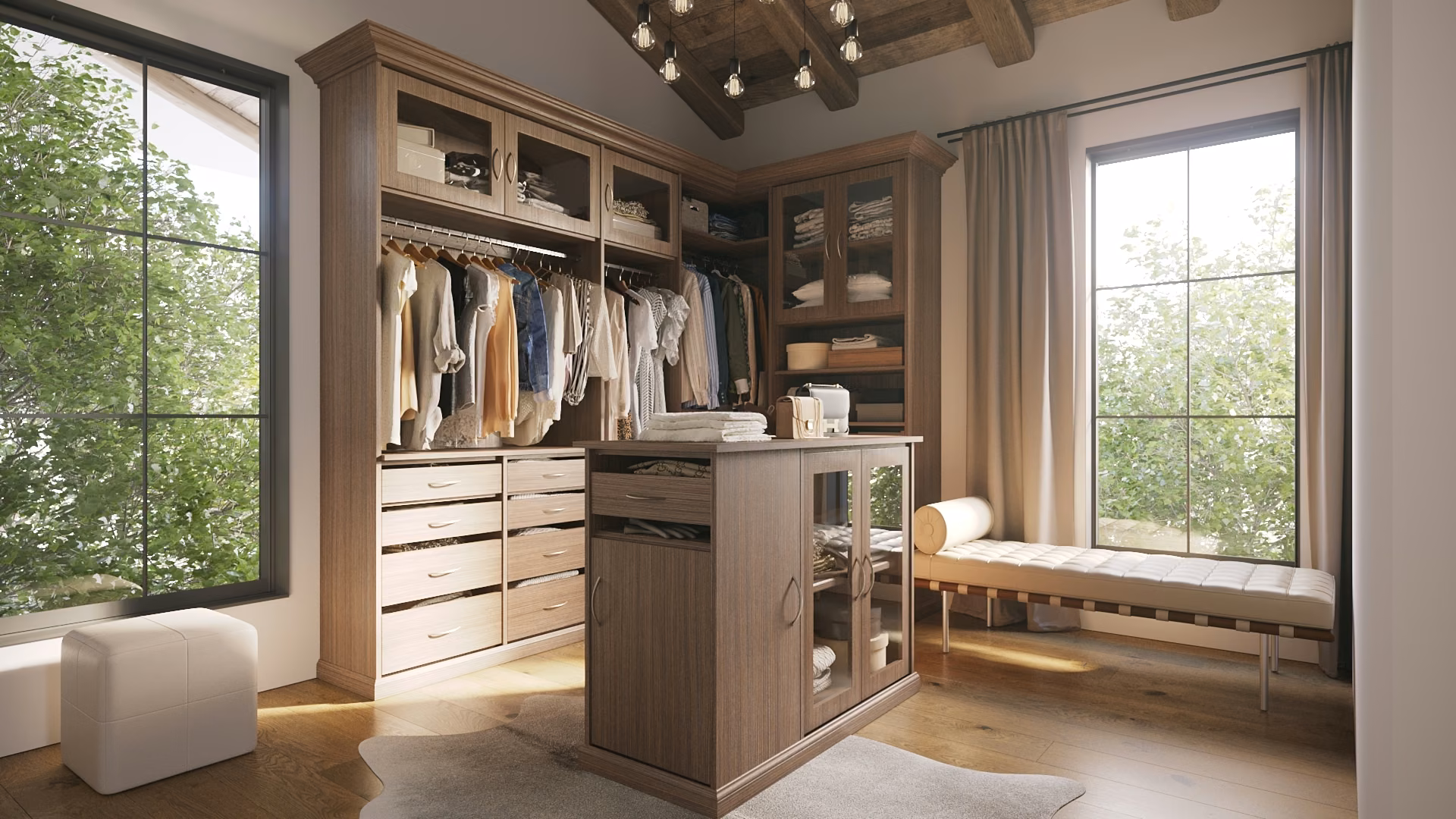A light wood walk-in closet with a center island topped with folded towels, glass-front cabinet doors below, a wall of drawers, an upholstered bench under a window, and exposed ceiling beams.