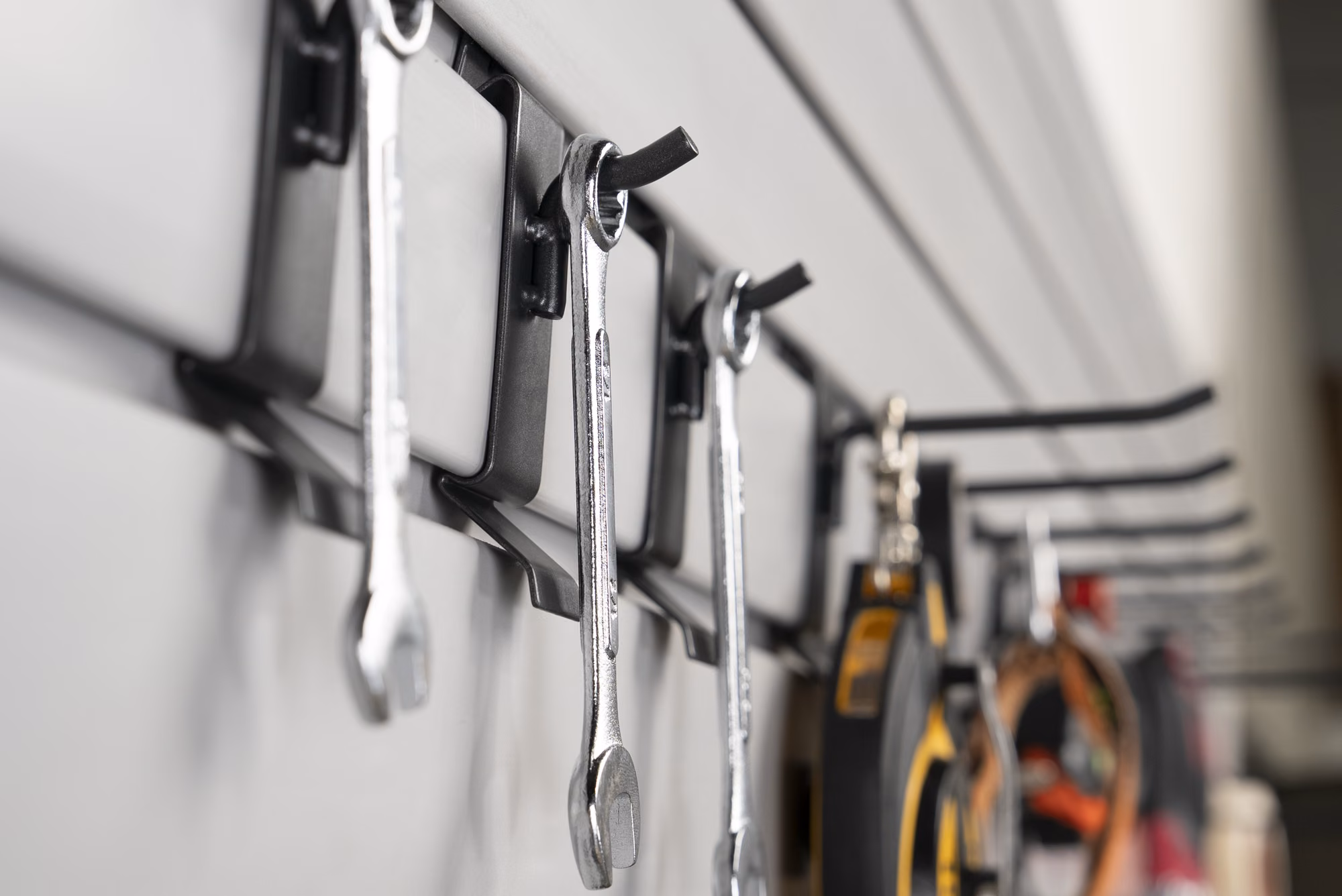 Close-up of wrenches and pliers hanging on individual slatwall hooks.