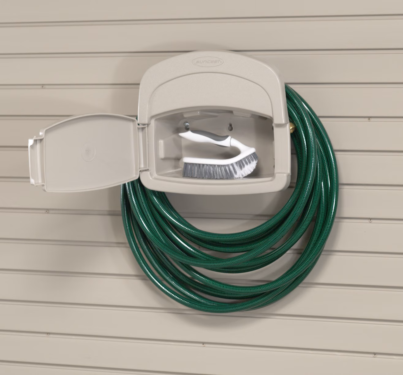 Wall-mounted holder with a green garden hose coiled on it.
