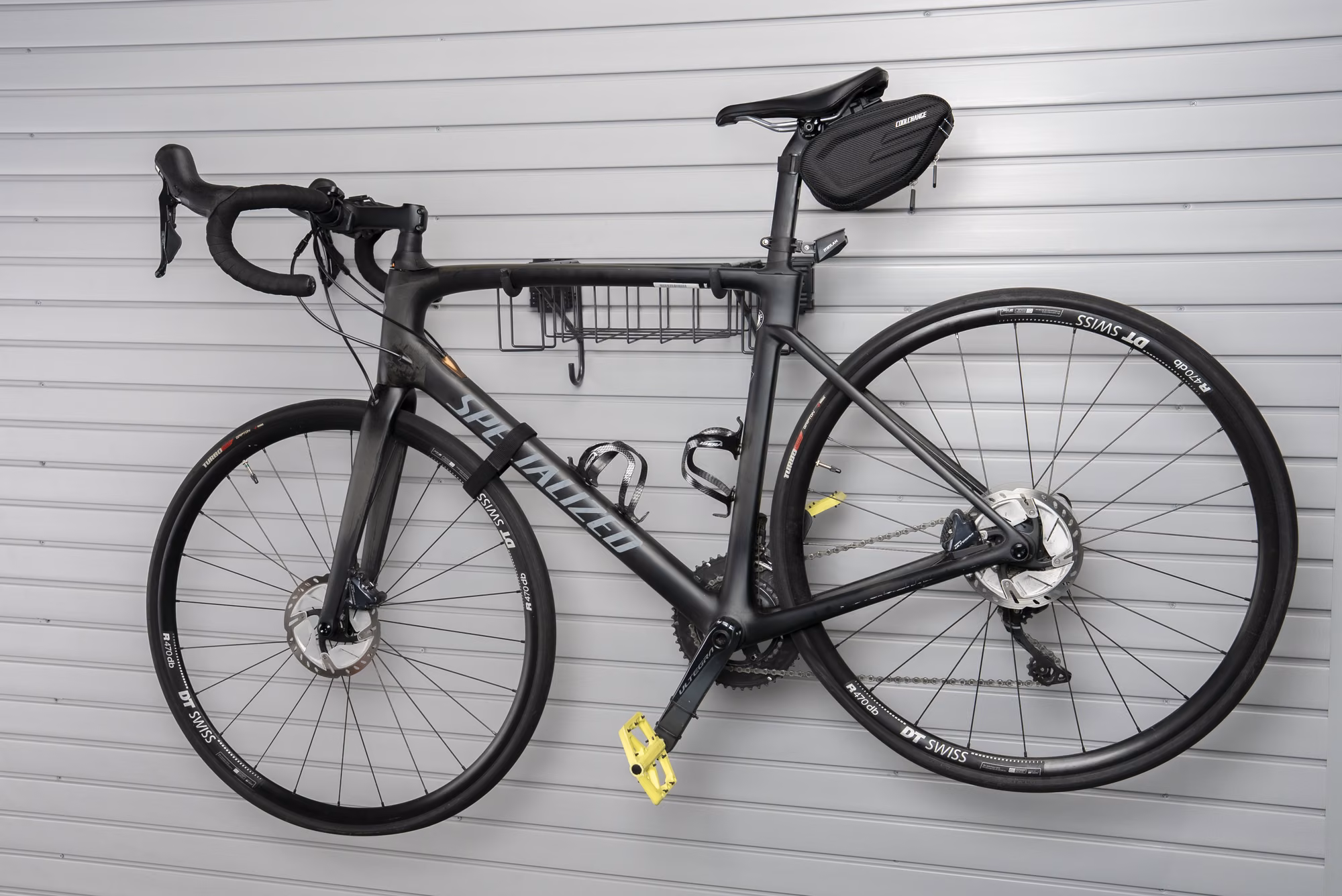 Road bike hung level on a slatwall bracket with both wheels off the floor.