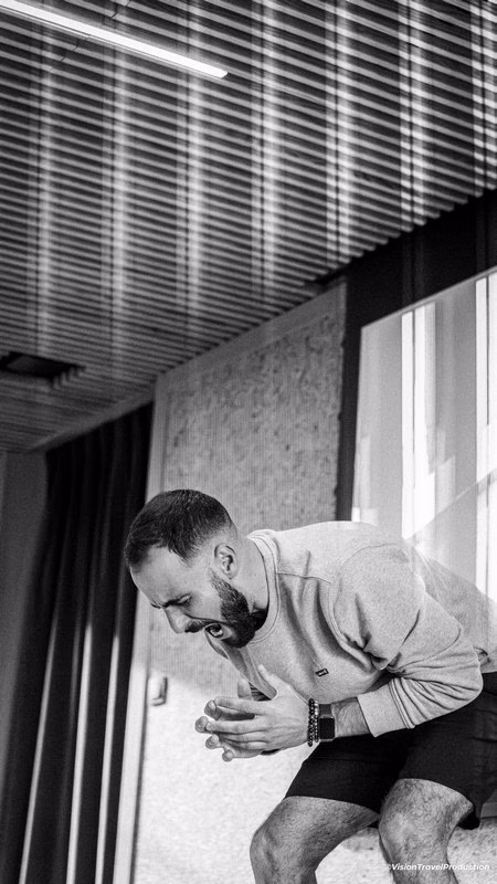 Photo en noir et blanc d'un homme barbu penché en avant, criant ou exprimant son enthousiasme à l'intérieur.