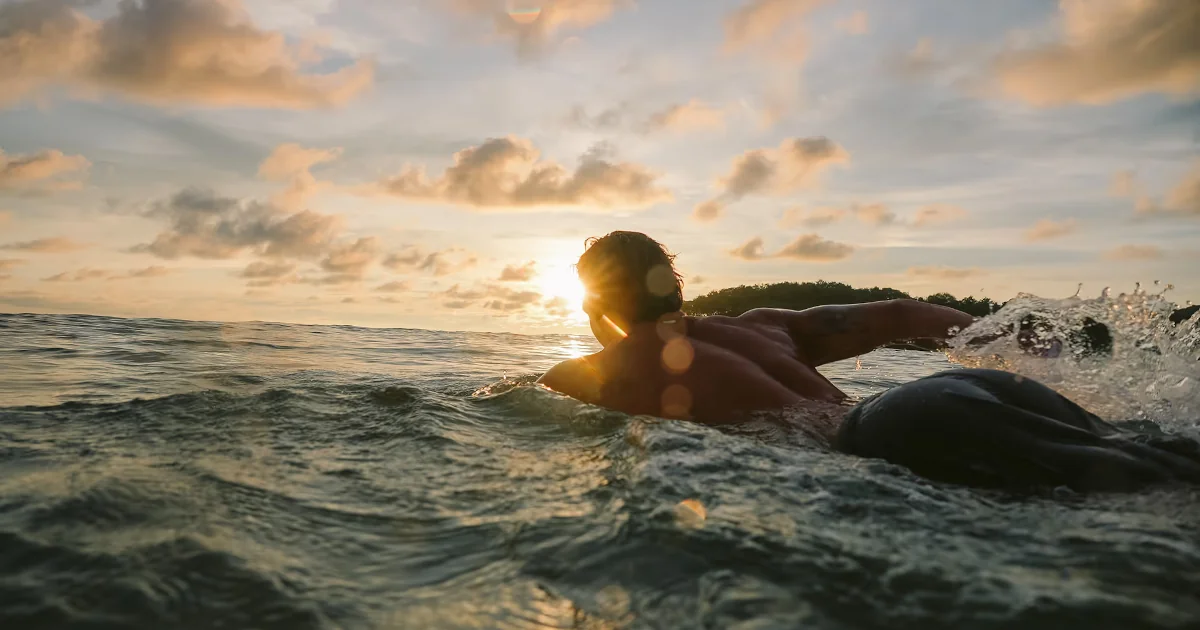 Surfer paddling out at golden hour in Costa Rica