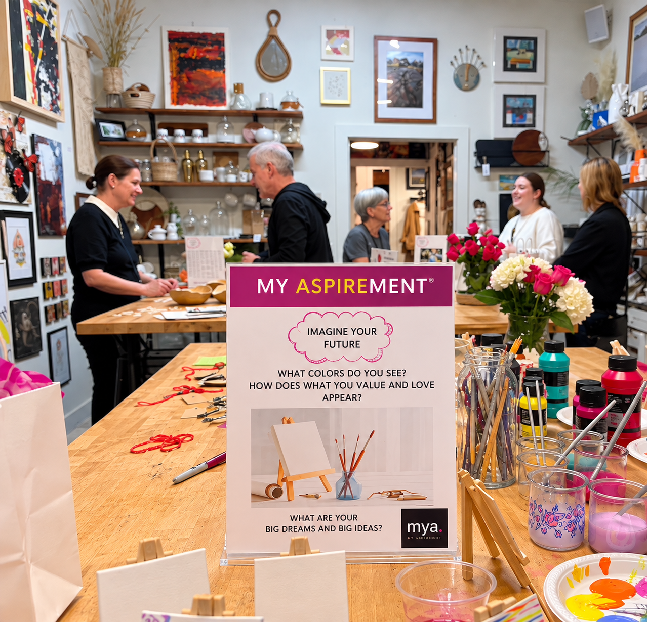 Creative workshop with participants, art materials and a MY ASPIREMENT sign inviting women to imagine their future.