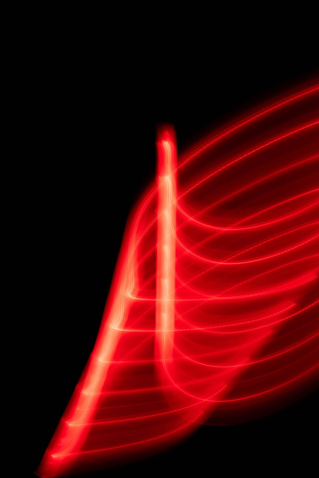 Abstract red light trails forming curved and straight lines on a black background.