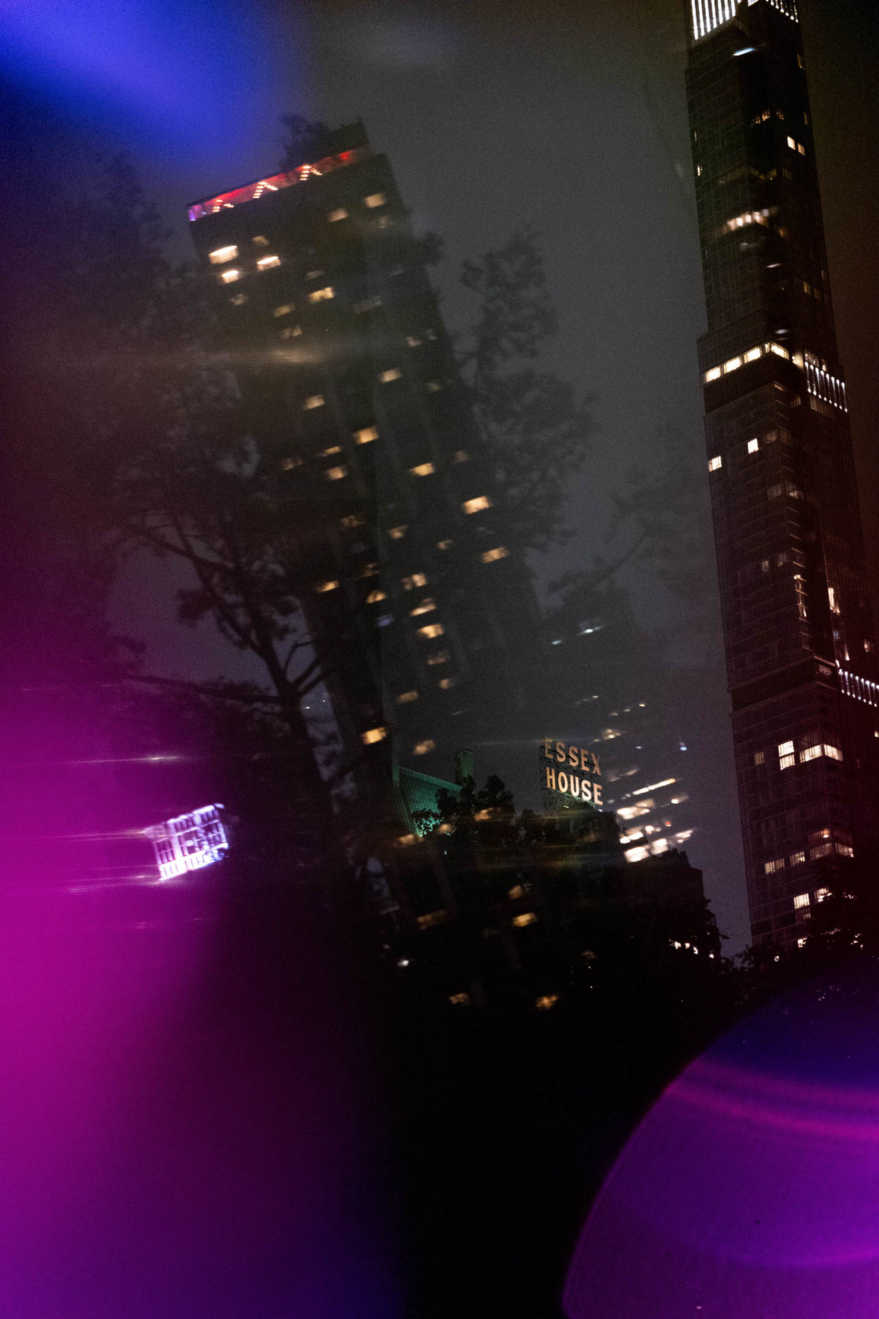 Night view of illuminated tall buildings  and purple light flares.