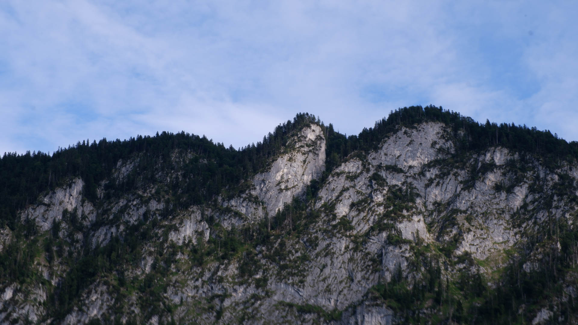 A mountain ridge against the sky with trees and rock faces.