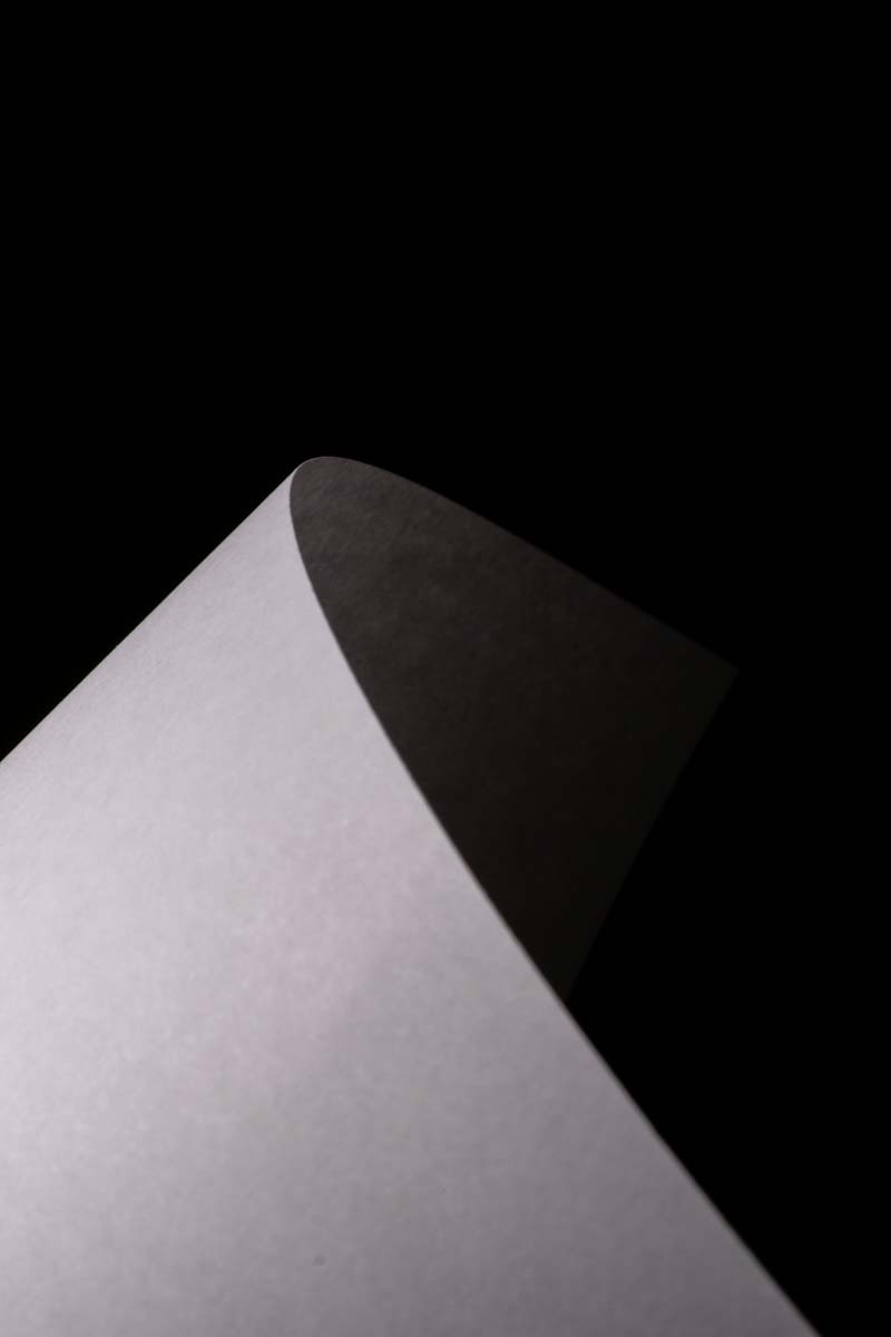 Curved sheet of white paper against a black background.