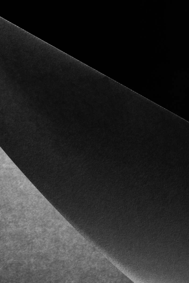 Close-up of textured black and gray overlapping sheets of paper or fabric.