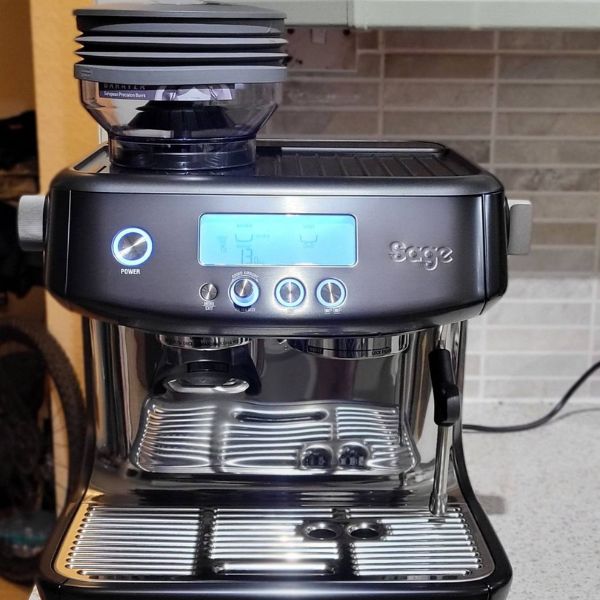 Crni Sage Barista Pro aparat za espresso sa osvetljenim ekranom i mlaznicom za paru, postavljen na kuhinjsku radnu površinu.
