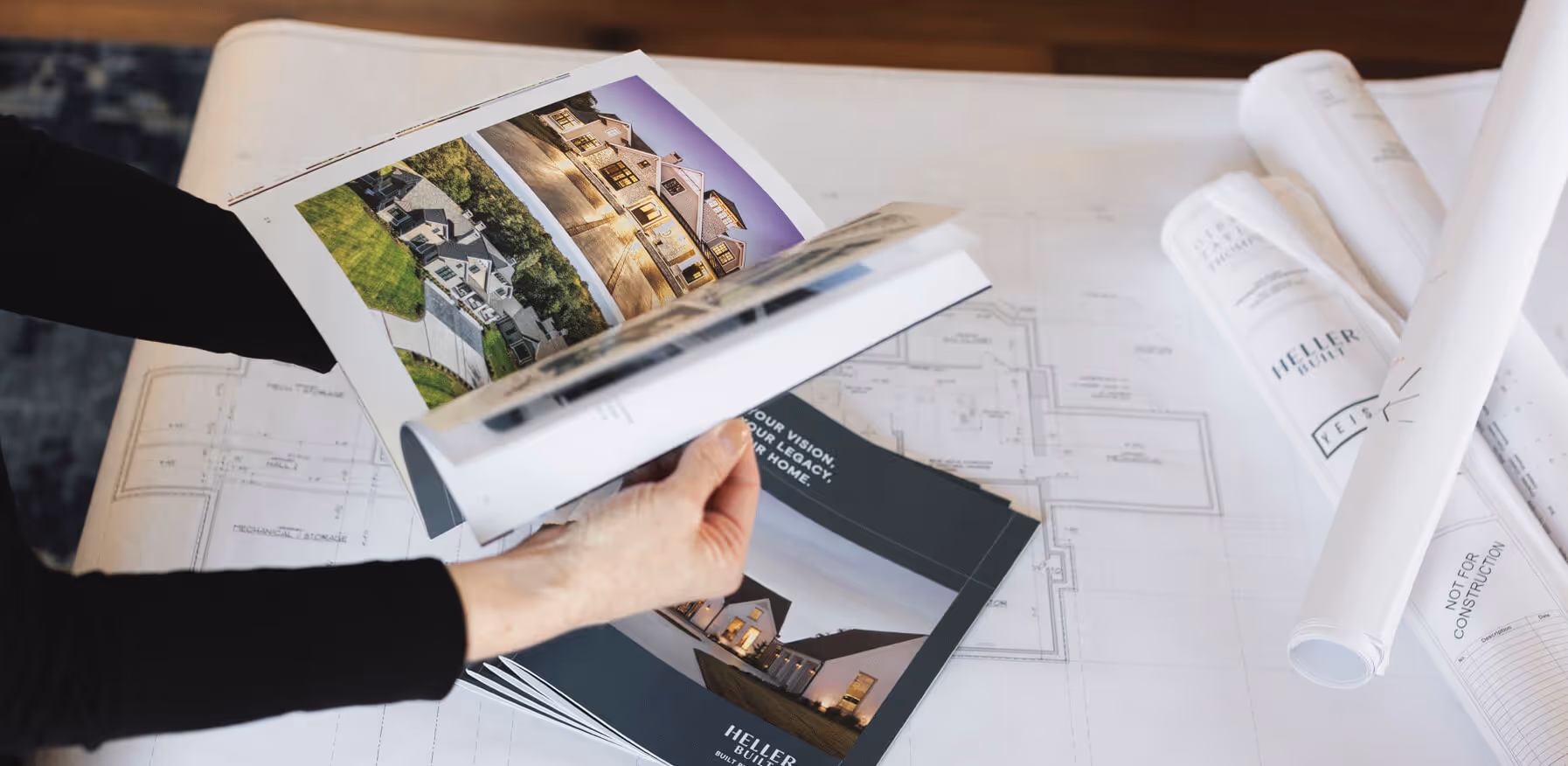 A photo of someone flipping through a booklet with homes pictured.