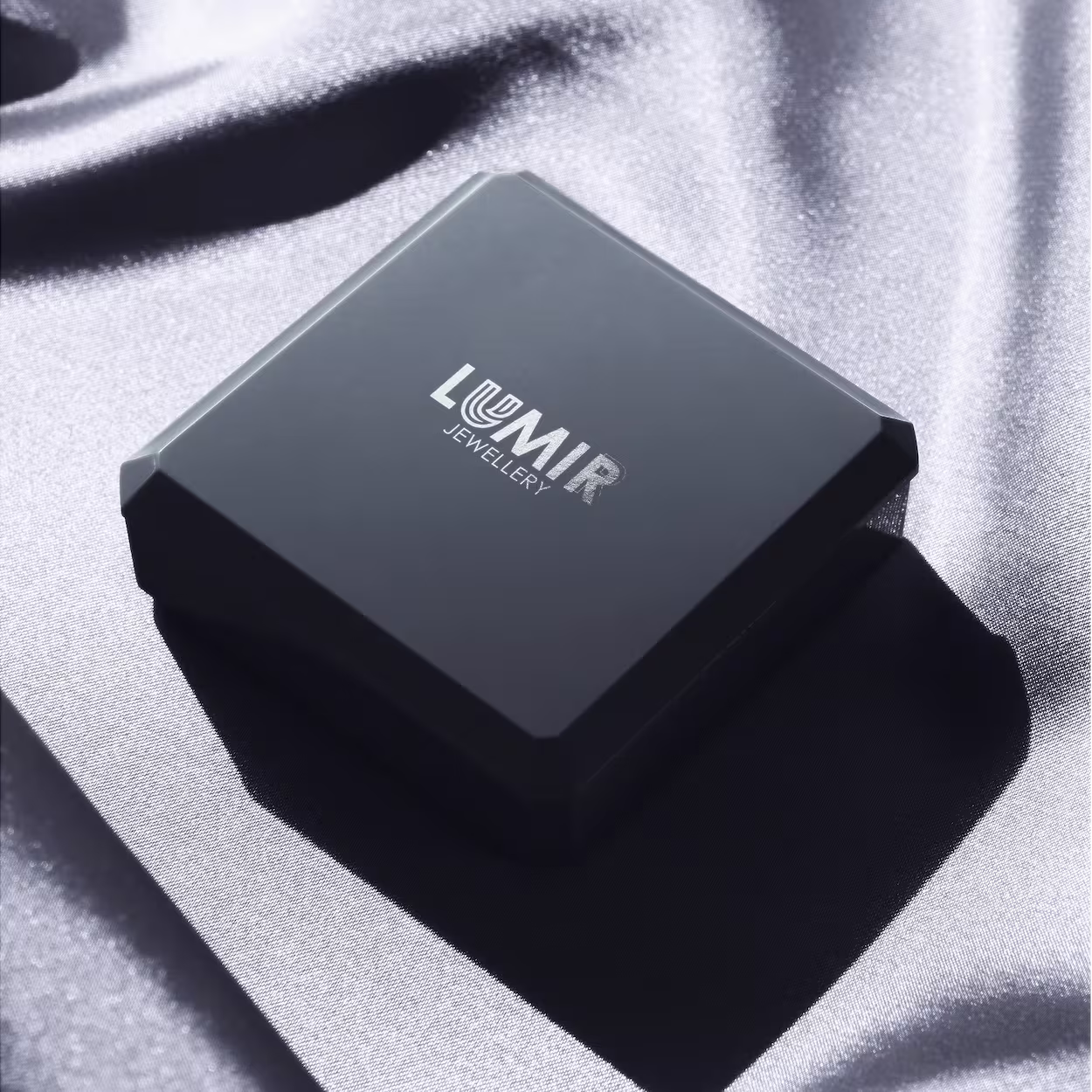 Closed black jewelry box with Lumir Jewellery logo on silver satin fabric.