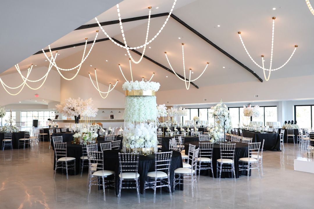 Ballroom with black-linen round tables, silver chairs and tall centrepieces