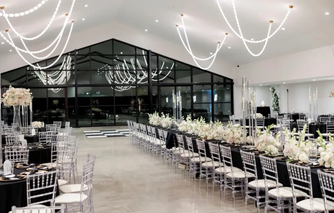 Ballroom with long banquet tables, silver chairs and white florals