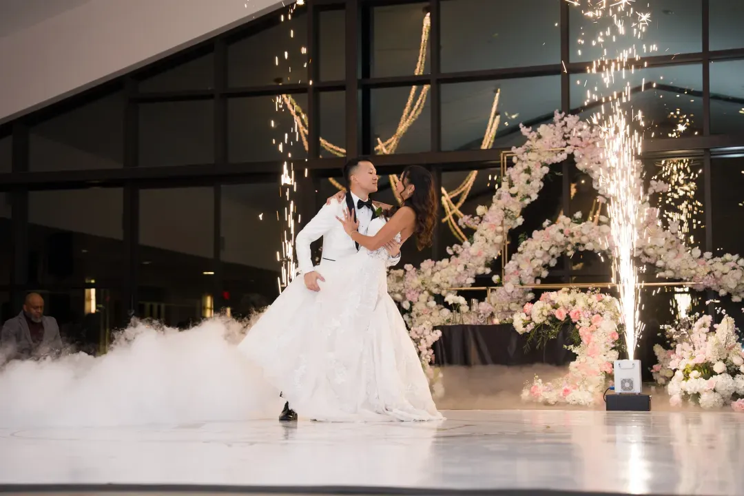 Couple sharing a first dance beside a floral arch
