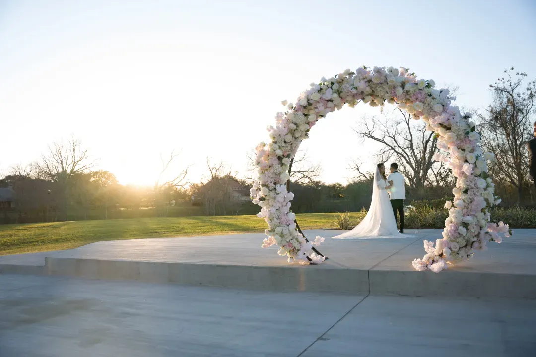 Bride and groom under a round floral arch on the outdoor ceremony deck