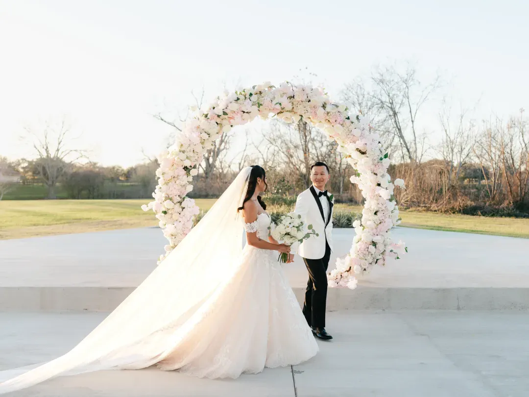 Bride and groom in front of a round pink and white floral arch