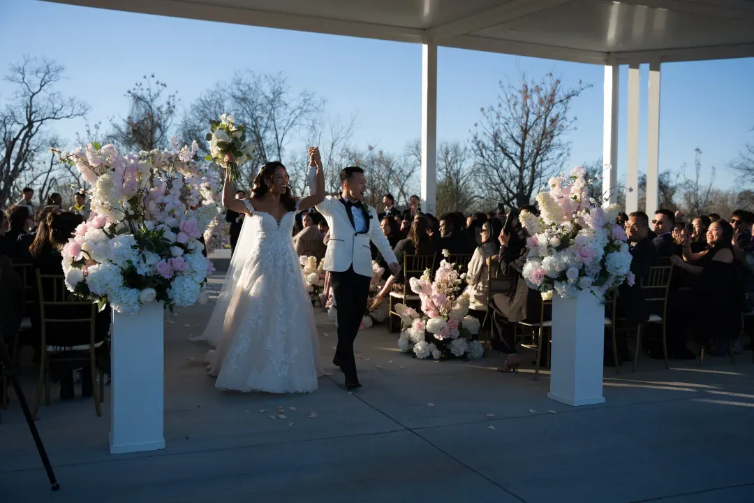 Bride and groom walking up the aisle past tall floral pillars
