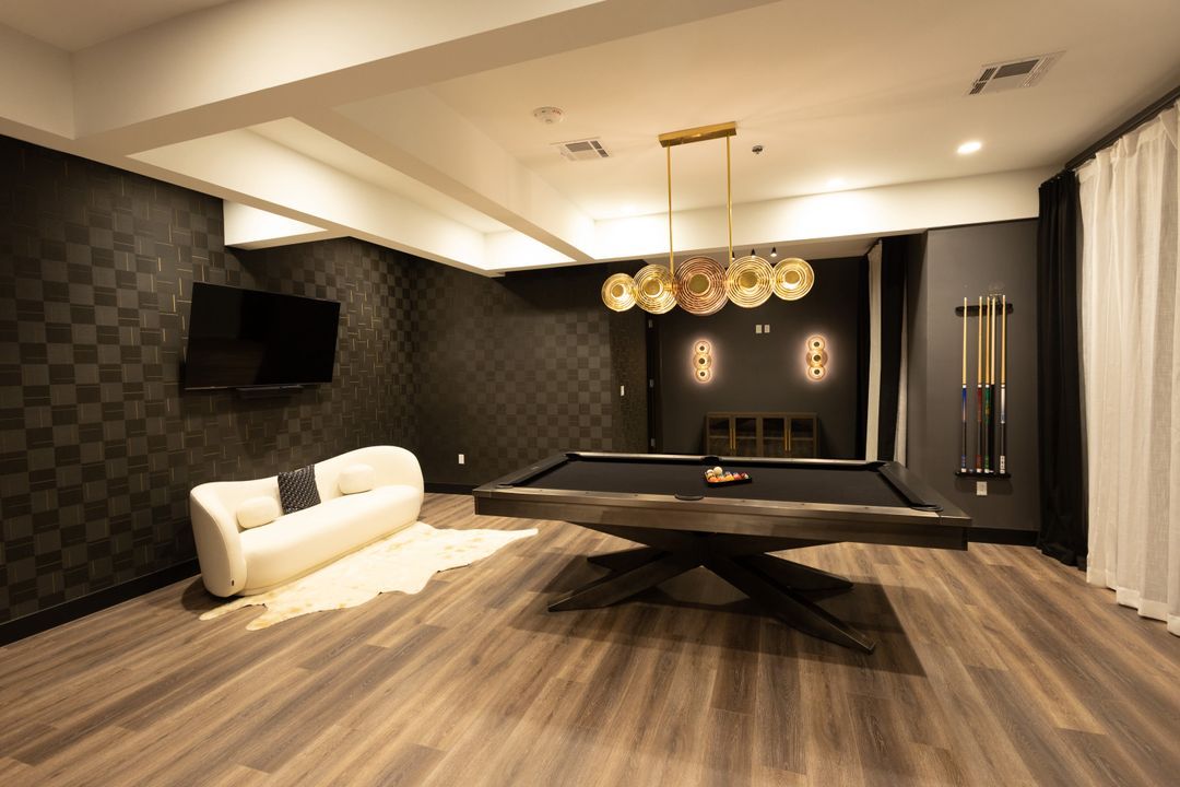 Groom's lounge with dark walls, a black pool table and gold pendant lights