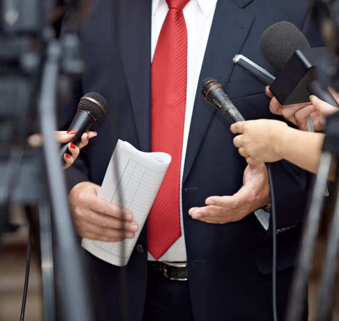 Image of microphones being held up to a reporter