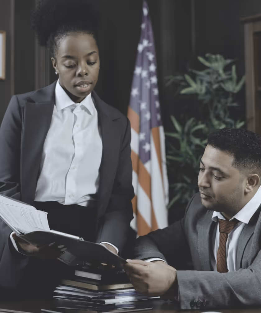 Image of a female lawyer showing documents to male lawyer with an American flag in the background