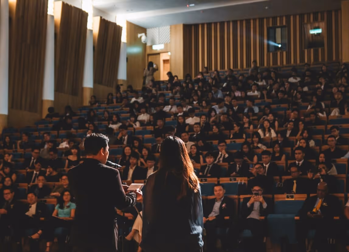 Image of presenters in front of a large crowd at a conference